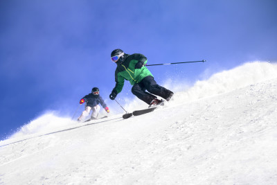 Two Skiers skiing downhill in high mountains and sunny day